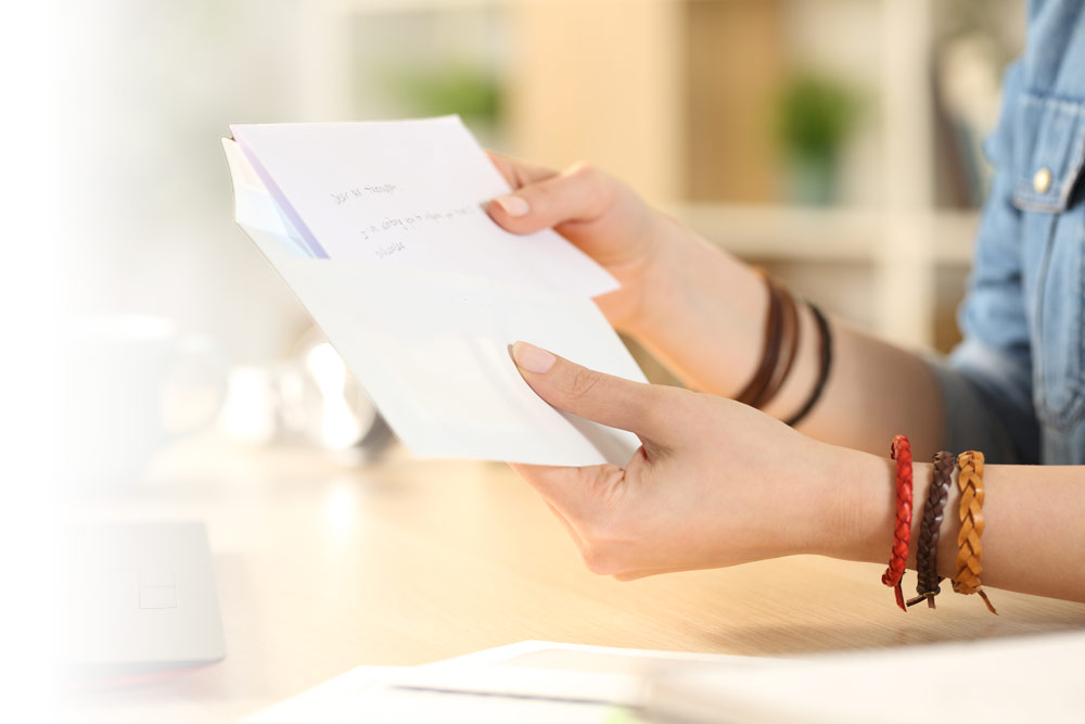 Placing thank you notes into envelope.